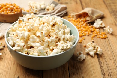 Photo of Tasty popcorn and corn kernels on wooden table, closeup