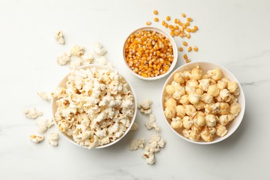 Photo of Tasty popcorn and corn kernels on white table, flat lay