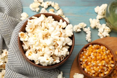 Photo of Tasty popcorn and corn kernels on blue wooden table, flat lay