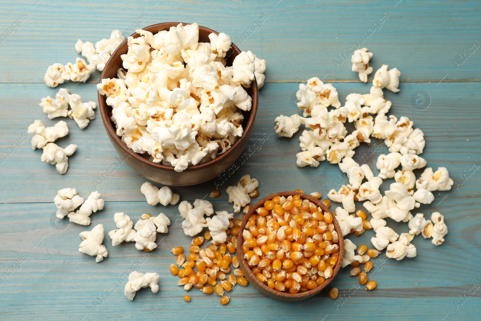 Tasty popcorn and corn kernels on blue wooden table, flat lay Photo of Tasty popcorn and corn kernels on blue wooden table, flat lay