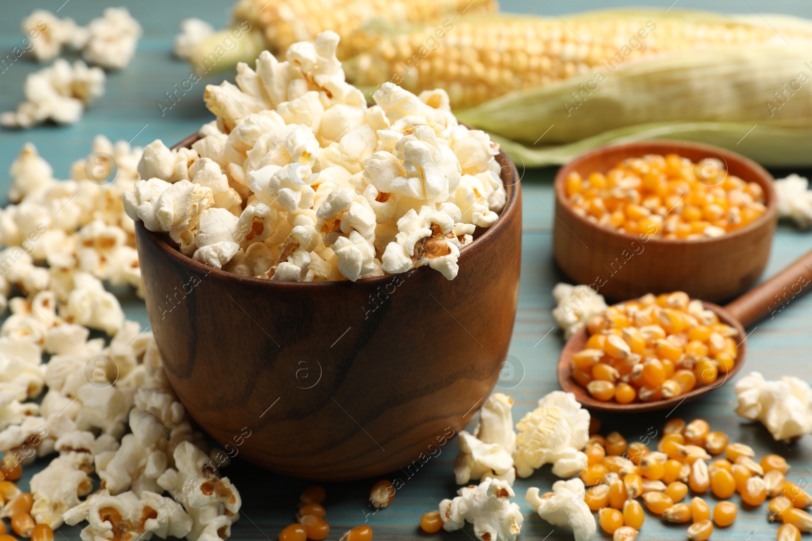 Tasty popcorn and corn kernels on blue wooden table, closeup Photo of Tasty popcorn and corn kernels on blue wooden table, closeup