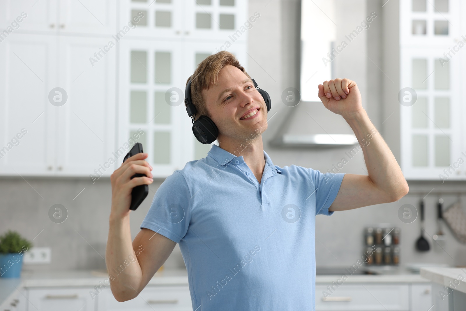 Happy man with smartphone listening to music in headphones and dancing at home Photo of Happy man with smartphone listening to music in headphones and dancing at home
