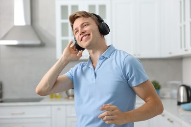 Photo of Happy man in headphones listening to music and dancing at home