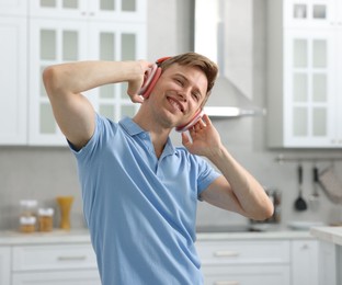 Photo of Happy man in headphones listening to music and dancing at home