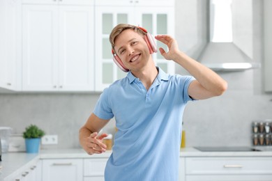 Photo of Happy man in headphones listening to music and dancing at home