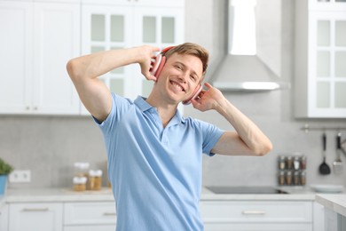 Photo of Happy man in headphones listening to music and dancing at home
