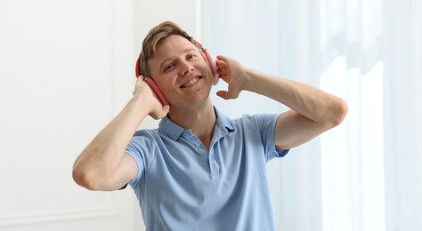 Photo of Happy man in headphones listening to music and dancing at home