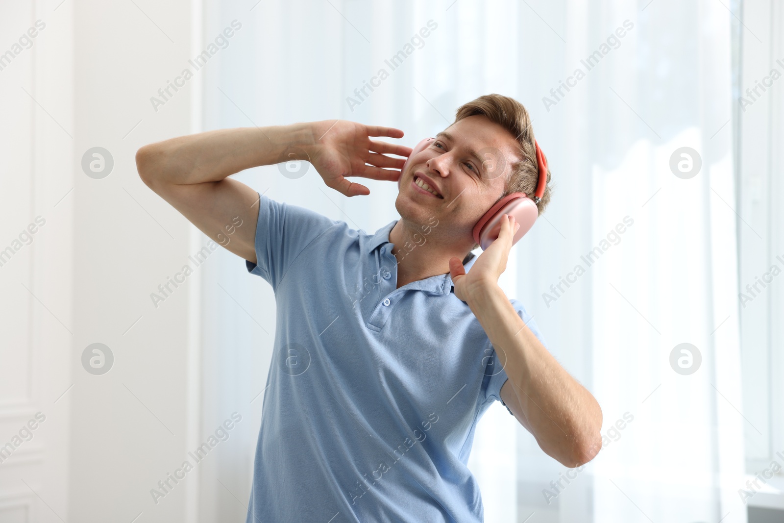 Happy man in headphones listening to music and dancing at home Photo of Happy man in headphones listening to music and dancing at home