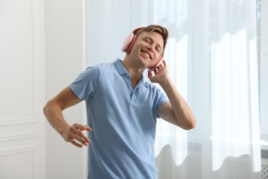 Photo of Happy man in headphones listening to music and dancing at home