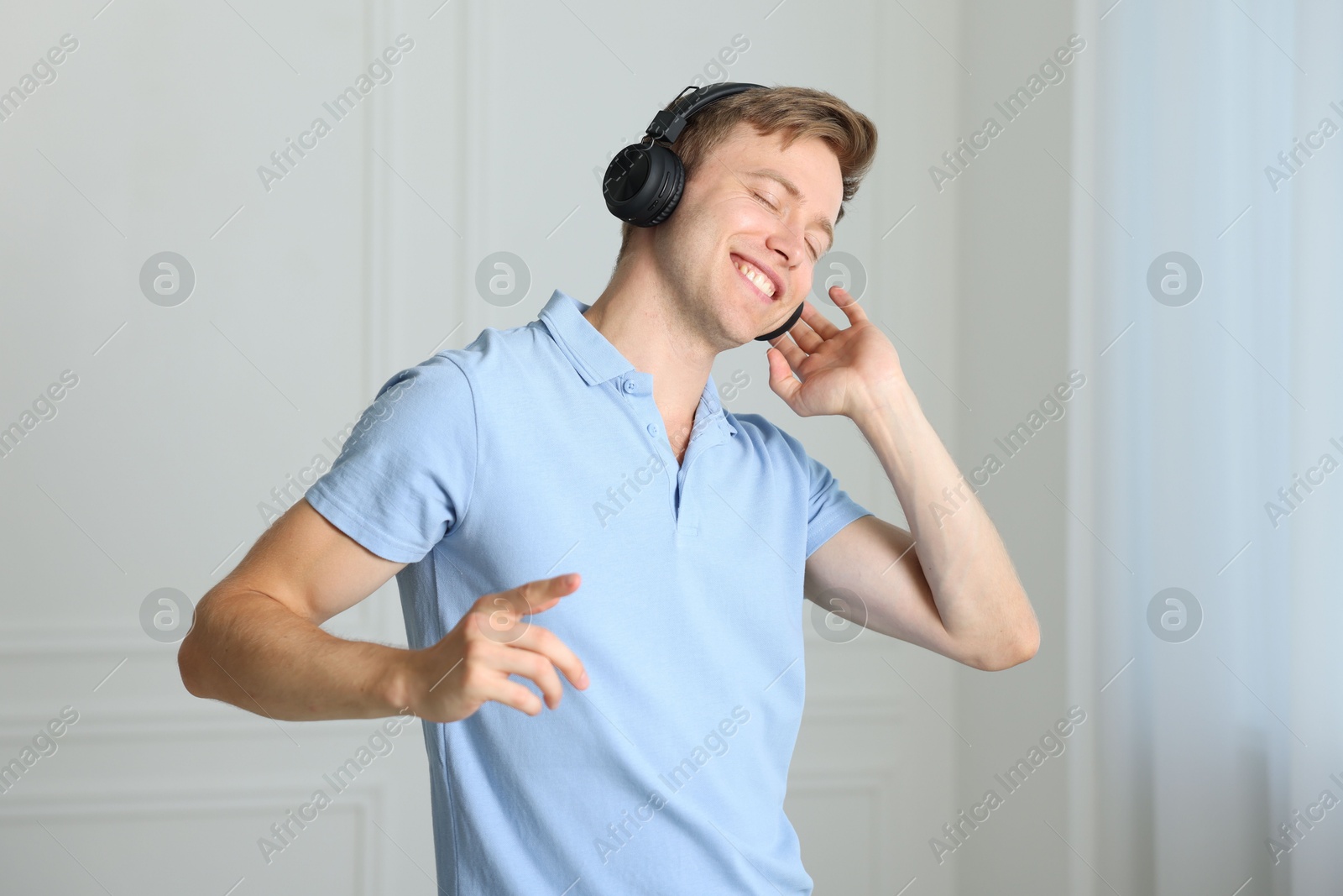 Happy man in headphones listening to music and dancing at home Photo of Happy man in headphones listening to music and dancing at home