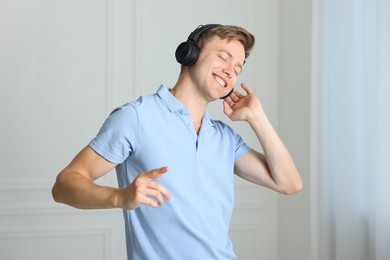 Photo of Happy man in headphones listening to music and dancing at home