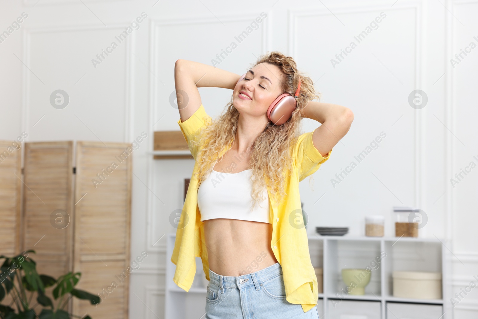 Photo of Happy woman in headphones listening to music and dancing at home