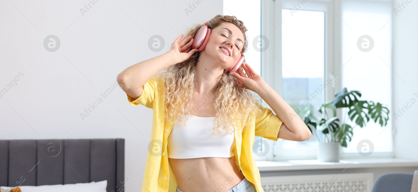 Photo of Happy woman in headphones listening to music and dancing at home