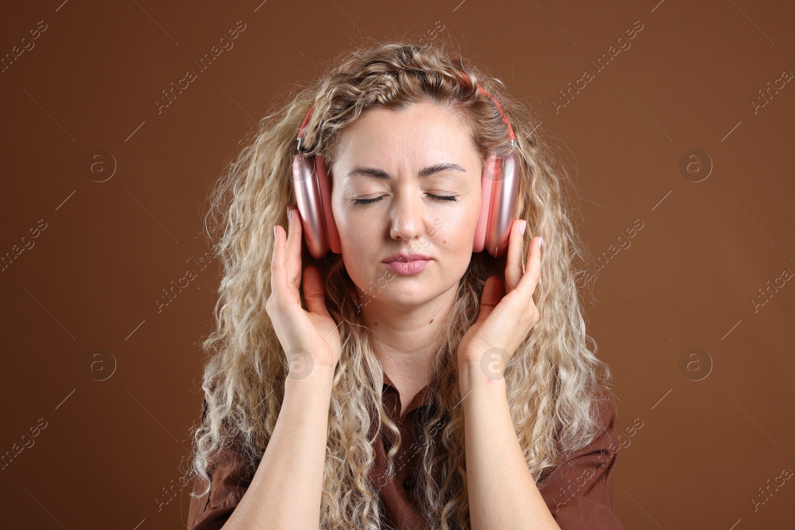 Photo of Beautiful woman listening to music in headphones on brown background