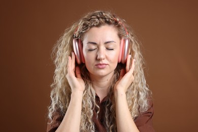 Photo of Beautiful woman listening to music in headphones on brown background