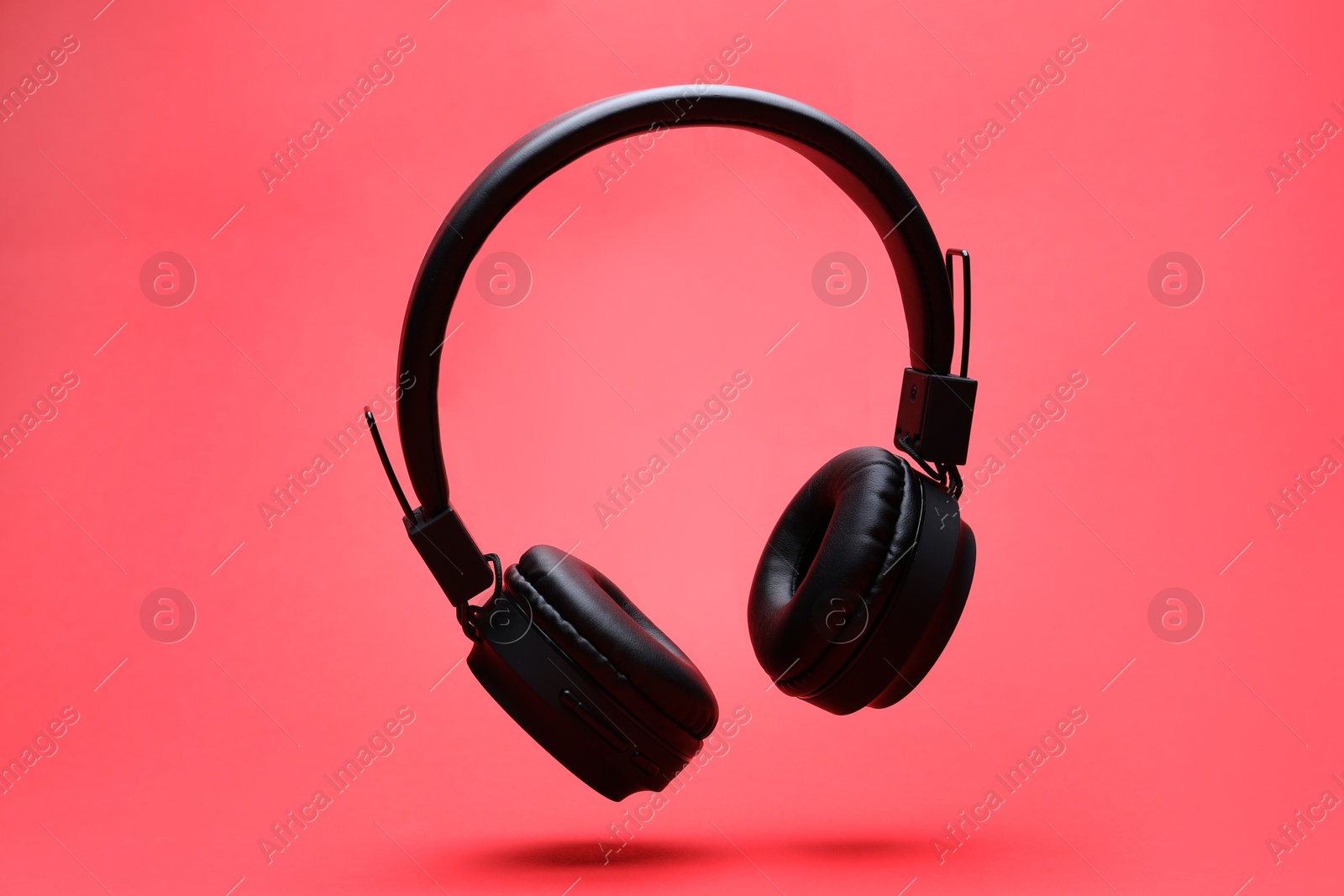 Pair of wireless headphones on coral background Photo of Pair of wireless headphones on coral background