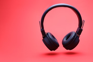 Photo of Pair of wireless headphones on coral background. Space for text
