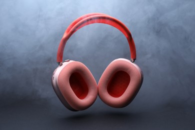 Photo of Pair of wireless headphones on grey background with smoke