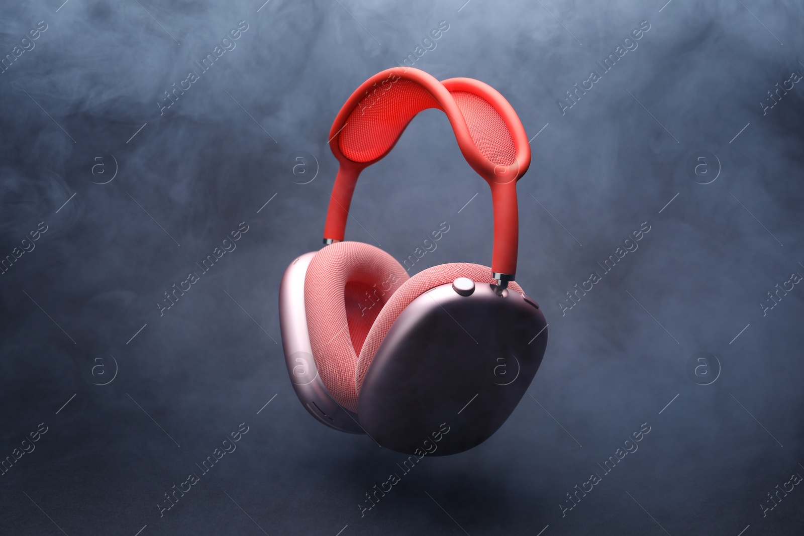 Pair of wireless headphones on grey background with smoke Photo of Pair of wireless headphones on grey background with smoke