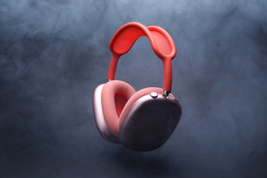 Photo of Pair of wireless headphones on grey background with smoke