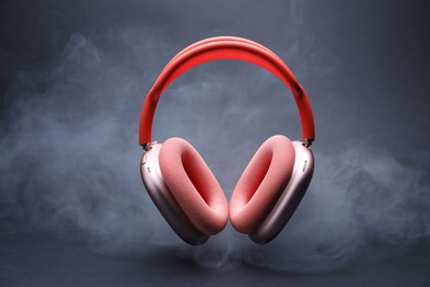 Photo of Pair of wireless headphones on grey background with smoke