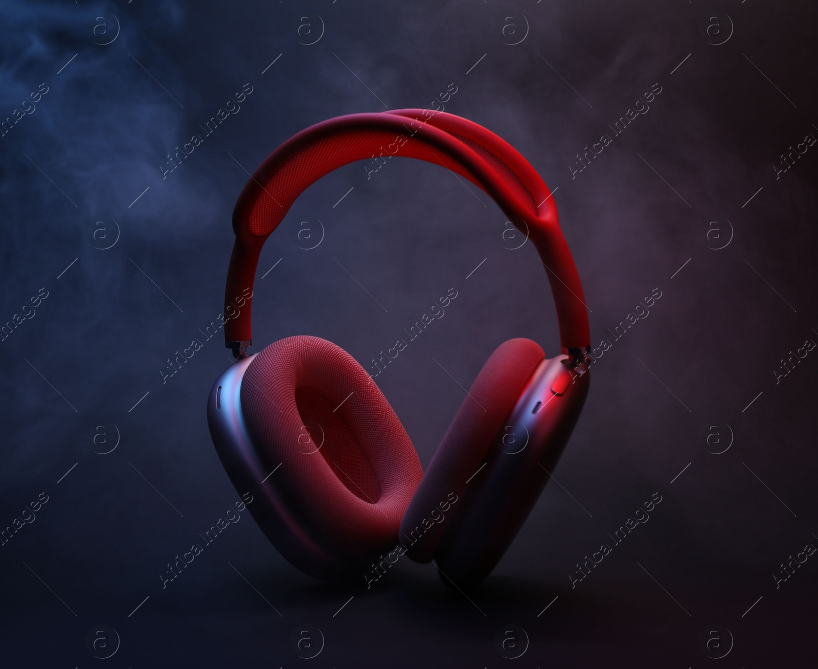 Pair of wireless headphones on dark background with color lights and smoke Photo of Pair of wireless headphones on dark background with color lights and smoke