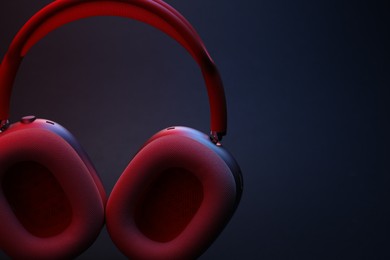 Photo of Pair of wireless headphones on dark background, closeup. Space for text