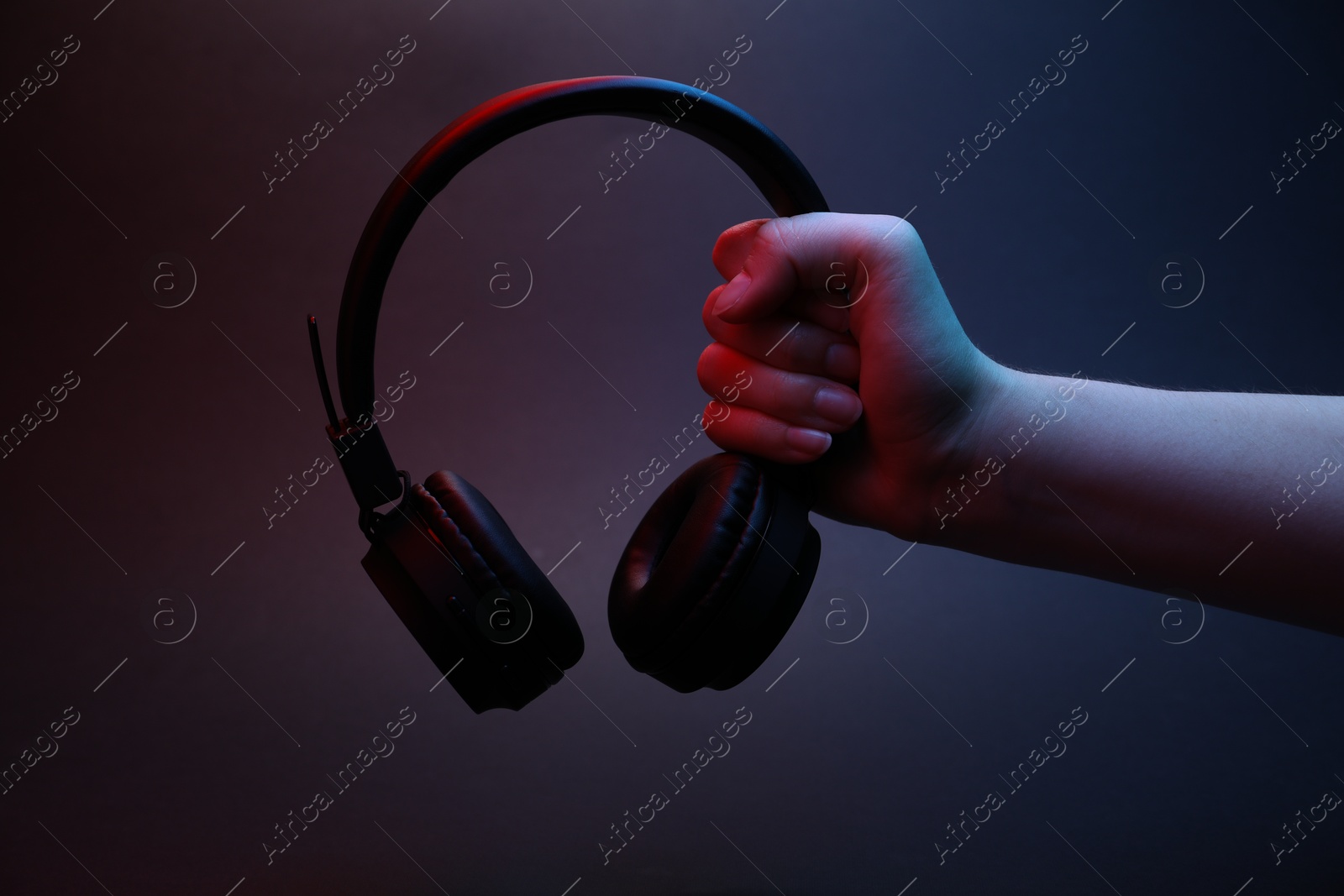 Woman holding wireless headphones on dark background, closeup Photo of Woman holding wireless headphones on dark background, closeup