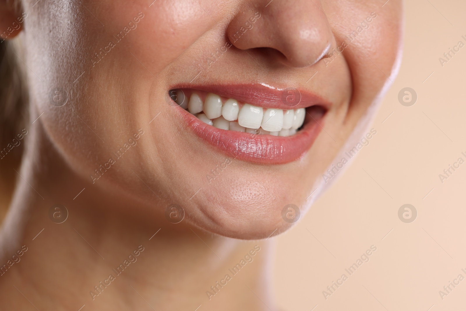Photo of Woman with beautiful healthy teeth on beige background, closeup