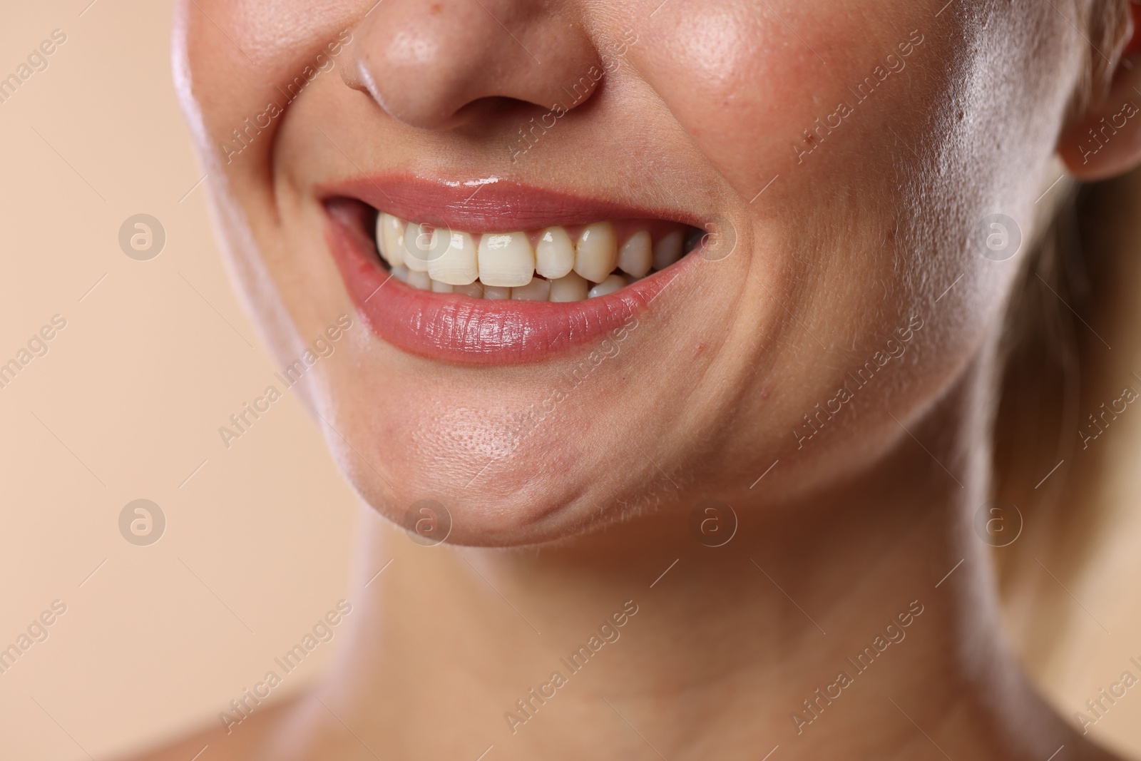 Photo of Woman with beautiful healthy teeth on beige background, closeup