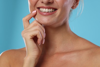 Photo of Woman with beautiful healthy teeth on light blue background, closeup