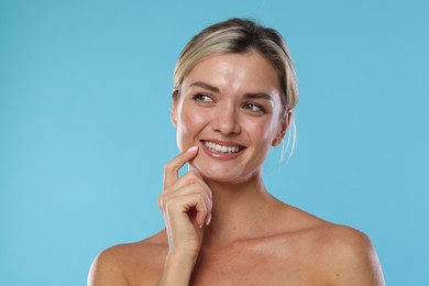 Photo of Woman with beautiful healthy teeth on light blue background