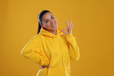 Photo of Woman with perfect healthy teeth showing okay gesture on yellow background