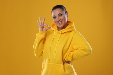 Photo of Woman with perfect healthy teeth showing okay gesture on yellow background