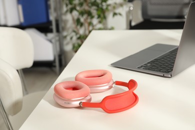 Photo of Wireless headphones and laptop on white background indoors, closeup. Space for text