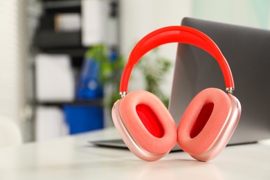 Photo of Laptop and wireless headphones on white background indoors, closeup. Space for text