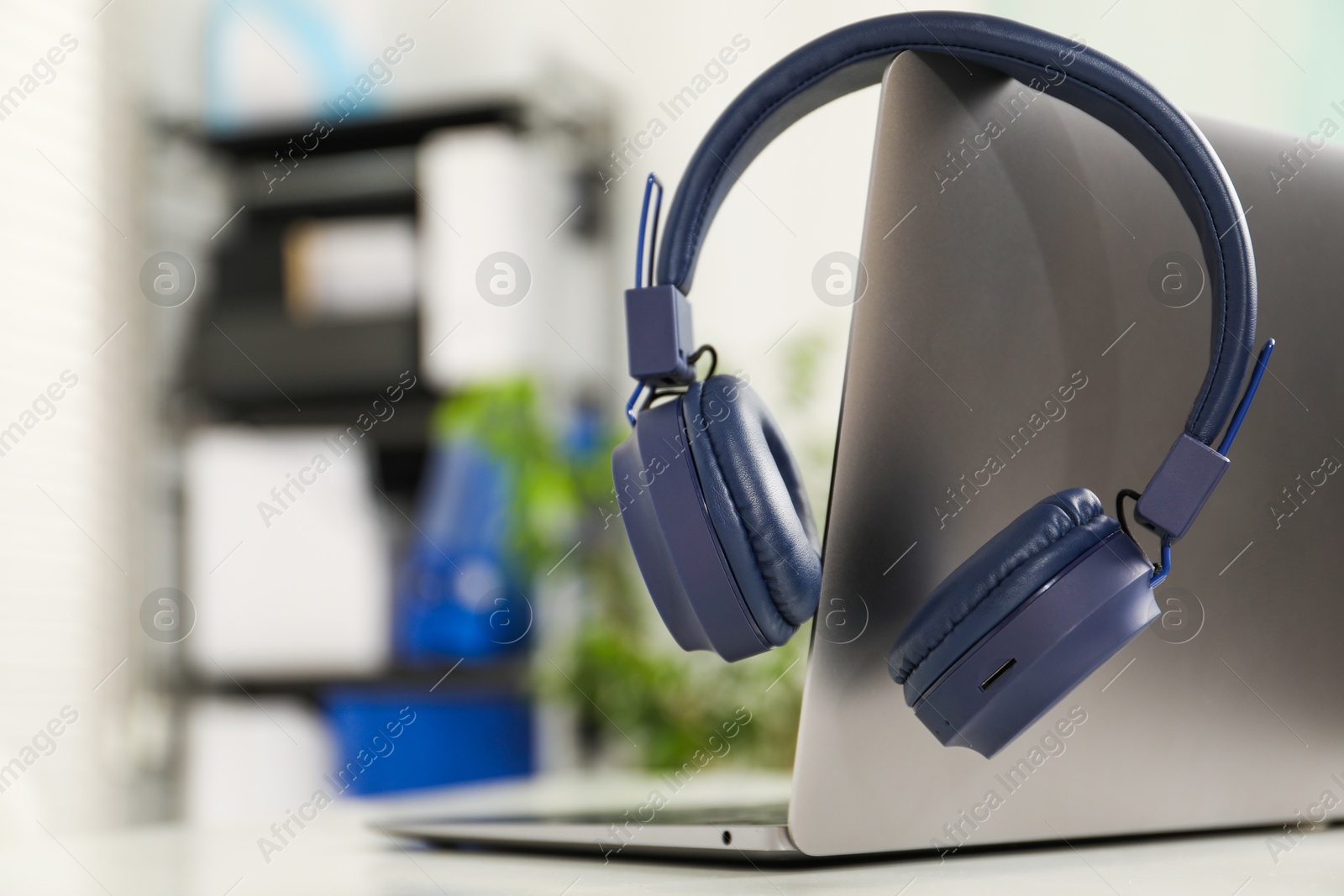 Laptop and wireless headphones on white background indoors, closeup. Space for text Photo of Laptop and wireless headphones on white background indoors, closeup. Space for text