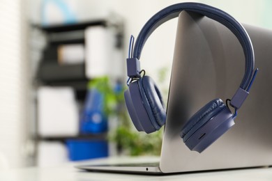 Photo of Laptop and wireless headphones on white background indoors, closeup. Space for text