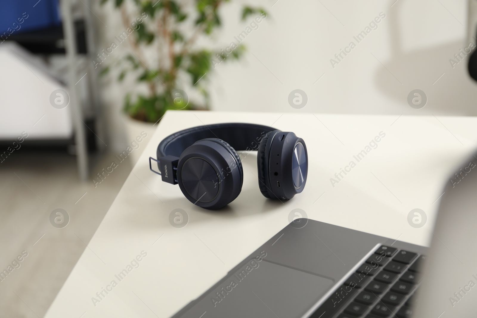 Wireless headphones and laptop on white background indoors, closeup Photo of Wireless headphones and laptop on white background indoors, closeup