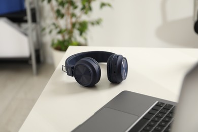 Photo of Wireless headphones and laptop on white background indoors, closeup