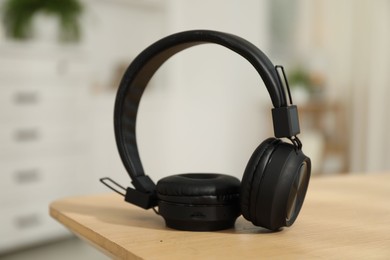 Photo of Modern wireless headphones on wooden table indoors, closeup