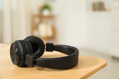 Photo of Modern wireless headphones on wooden table indoors, closeup. Space for text
