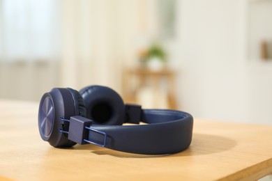 Photo of Modern wireless headphones on wooden table indoors, closeup. Space for text