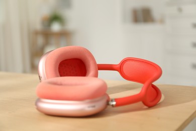 Photo of Modern wireless headphones on wooden table indoors, closeup