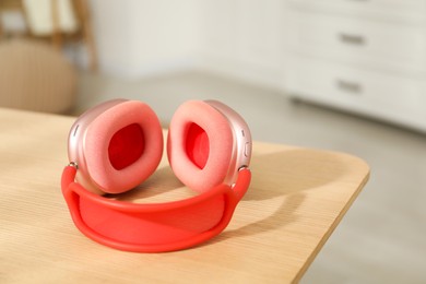 Photo of Modern wireless headphones on wooden table indoors, closeup. Space for text