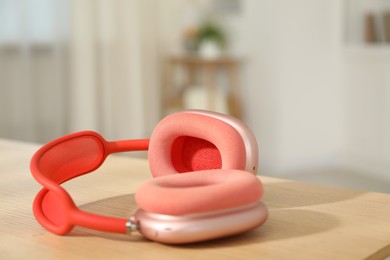 Photo of Modern wireless headphones on wooden table indoors, closeup. Space for text