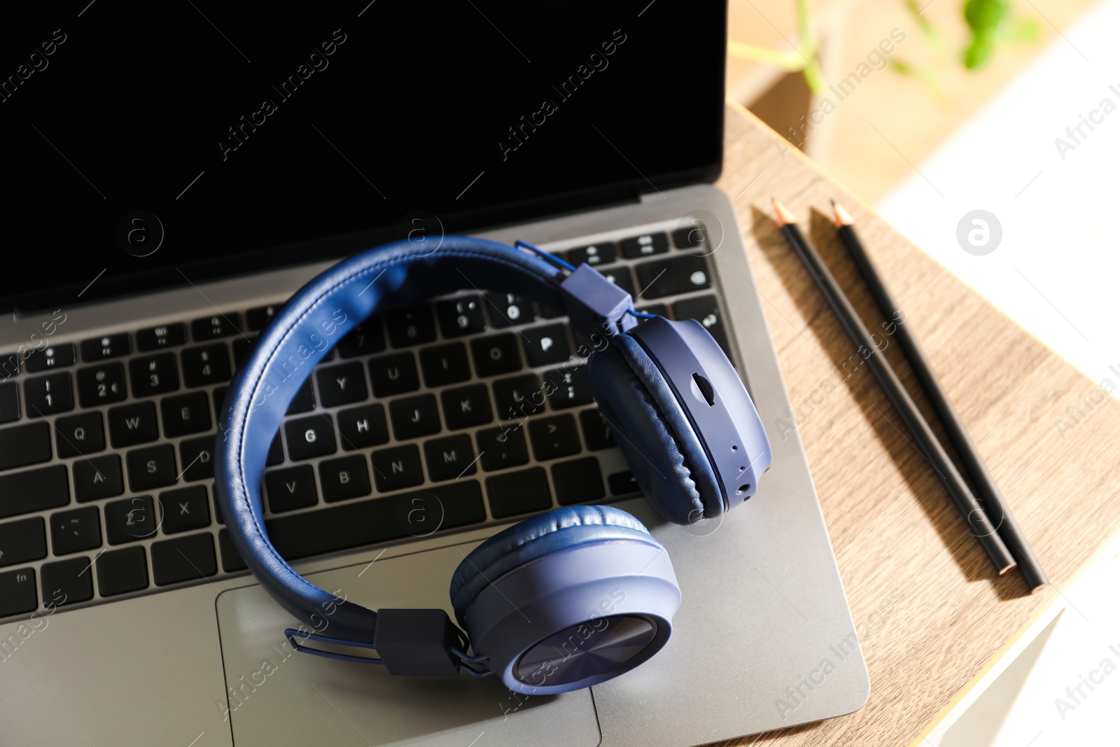Laptop, wireless headphones and pencils on wooden table indoors, closeup Photo of Laptop, wireless headphones and pencils on wooden table indoors, closeup