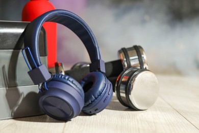 Photo of Wireless headphones, step platform, dumbbells and bottle of water on floor in gym, closeup