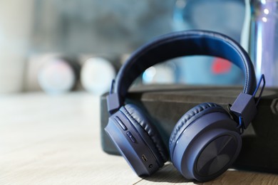 Photo of Wireless headphones, yoga block and bottle of water on floor in gym, closeup. Space for text