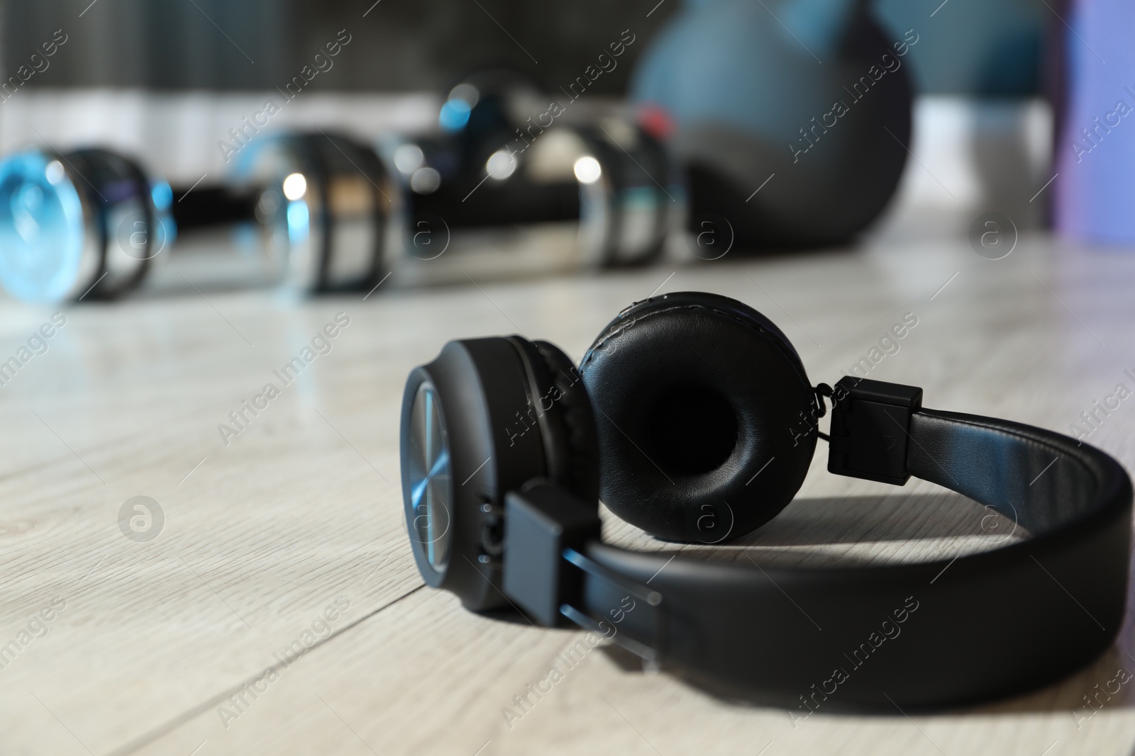Wireless headphones on floor in gym, closeup. Space for text Photo of Wireless headphones on floor in gym, closeup. Space for text